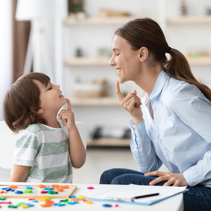 A child and therapist practicing communication skills at a table